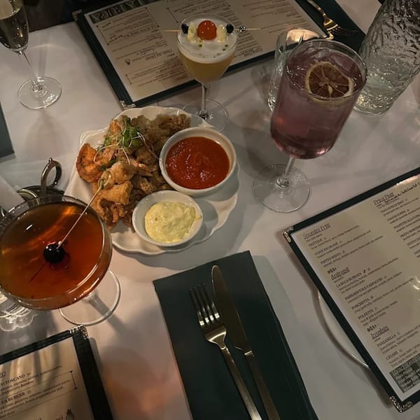 An overhead view of a table set with cocktails, fried calamari, and menus at La Buca restaurant.